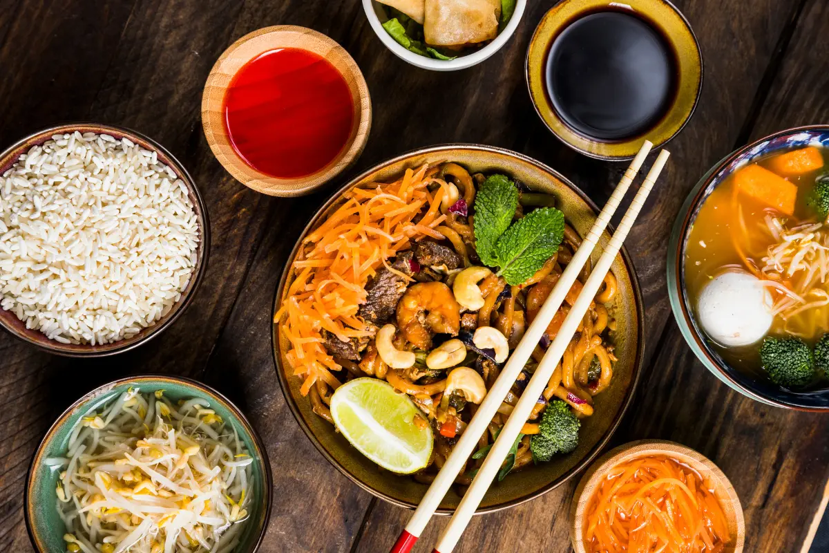 A rustic wooden table laden with bowls of colorful and vibrant Thai food, ready to be shared and enjoyed.