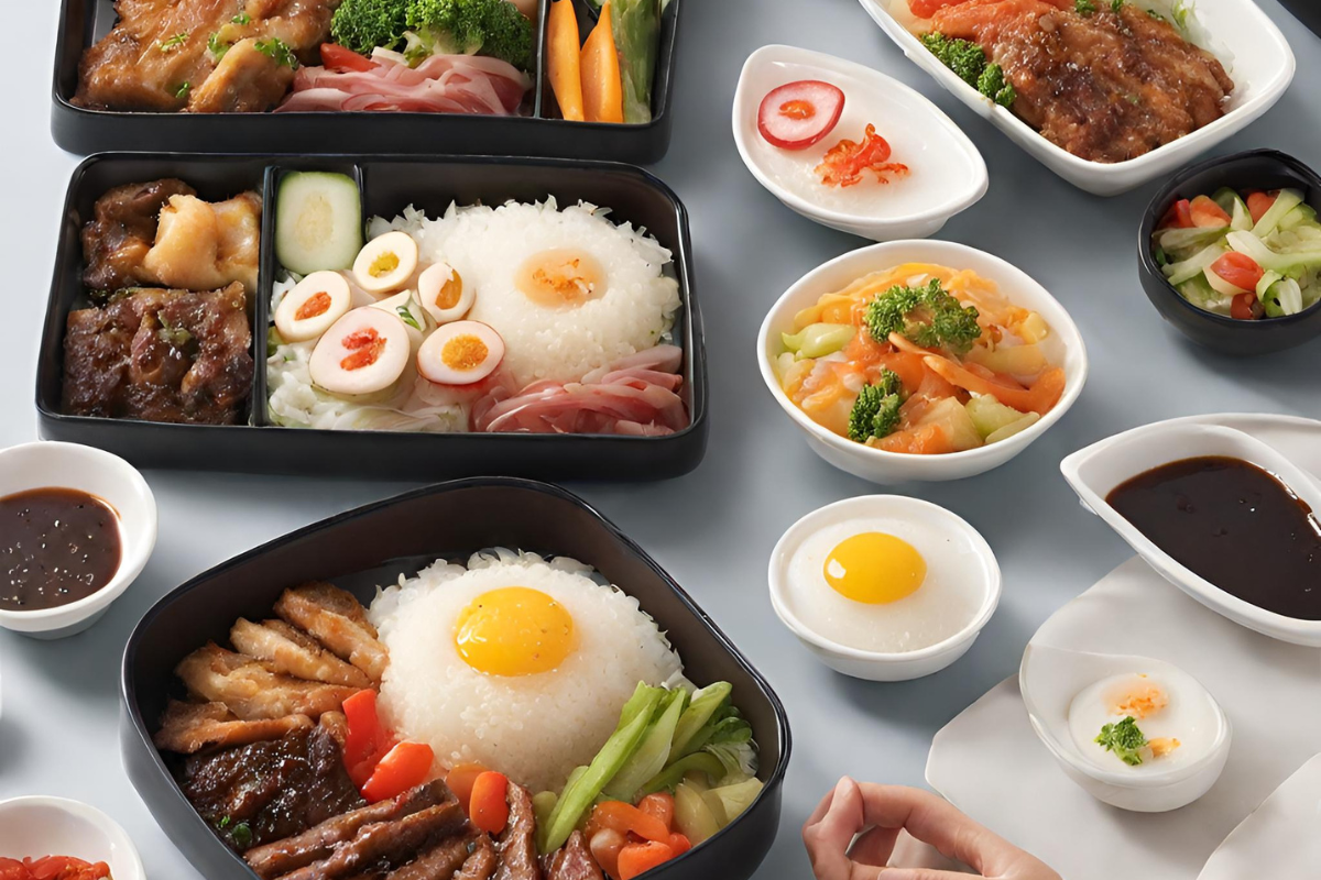 A table with a variety of food on it, including rice, eggs, meat, and vegetables. The table is set for a meal, with plates, napkins, and silverware. The food is arranged in a colorful and appetizing way.